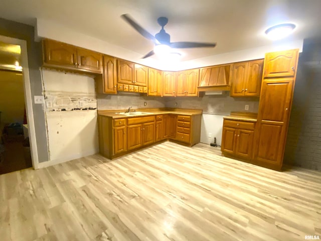 kitchen featuring a sink, brown cabinetry, custom exhaust hood, and light wood-style flooring