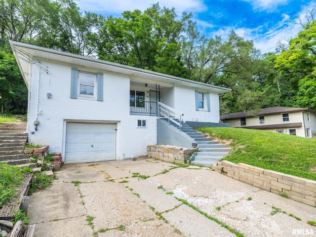 view of front of home featuring stairs, concrete driveway, an attached garage, and brick siding