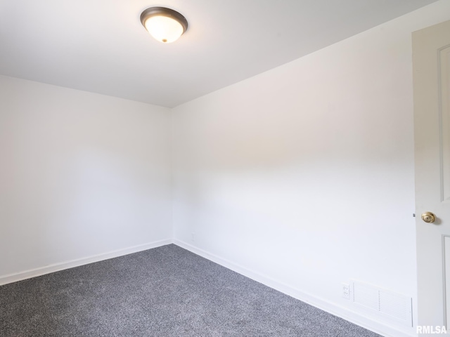 empty room featuring visible vents, dark carpet, and baseboards