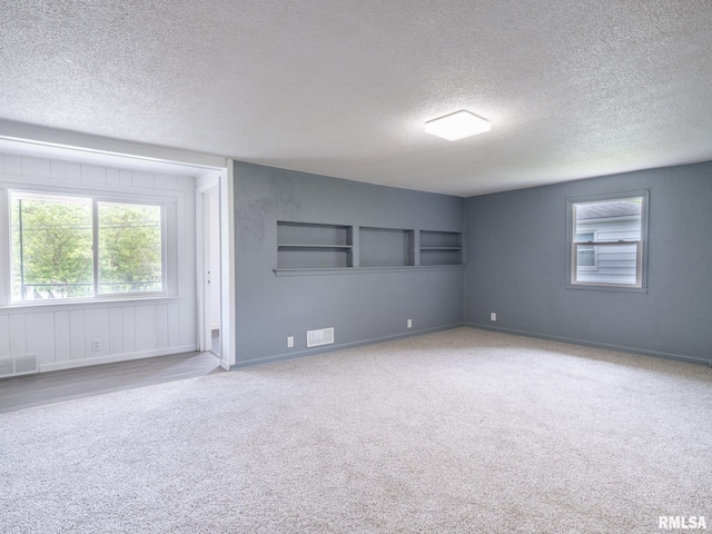 spare room with visible vents, carpet flooring, a textured ceiling, and baseboards