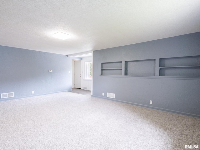 empty room featuring visible vents, a textured ceiling, and carpet