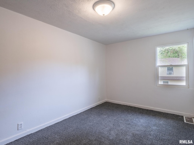 spare room with baseboards, visible vents, dark colored carpet, and a textured ceiling