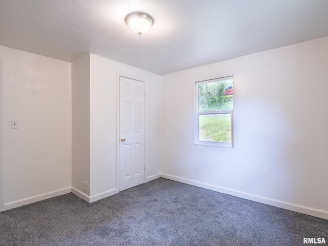 unfurnished room featuring baseboards and dark colored carpet