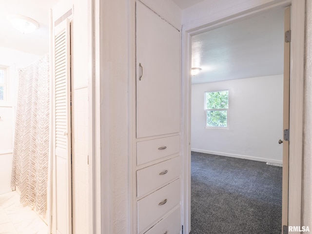 hallway with carpet flooring and baseboards