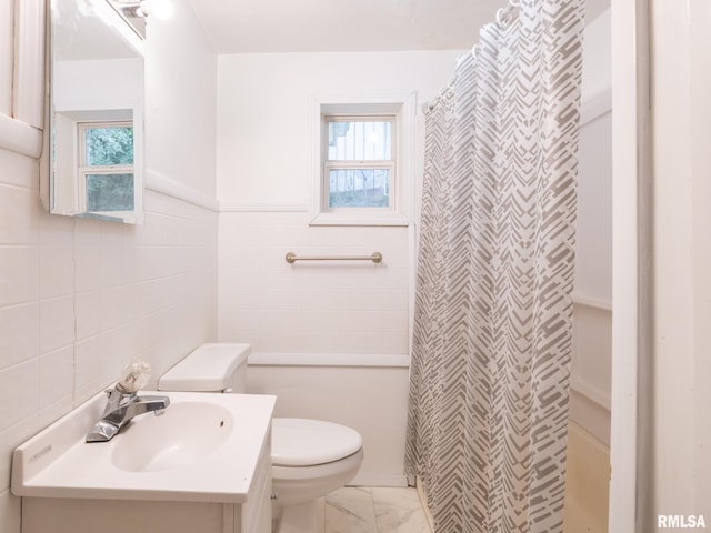 full bath featuring plenty of natural light, toilet, marble finish floor, and tile walls