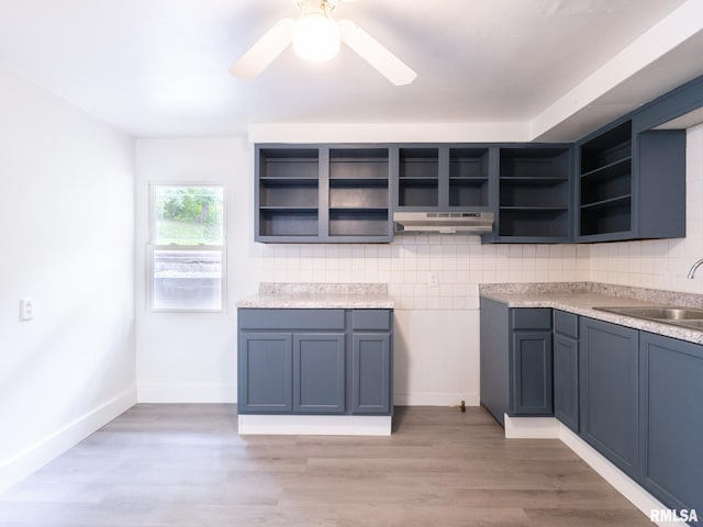 kitchen featuring open shelves, light wood finished floors, backsplash, and a sink
