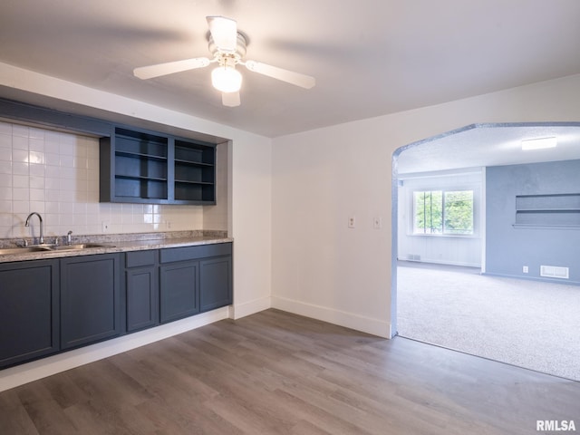 kitchen with tasteful backsplash, visible vents, a sink, wood finished floors, and open shelves
