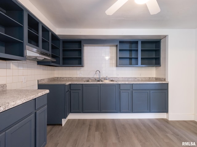 kitchen featuring open shelves, light wood-style floors, under cabinet range hood, and a sink