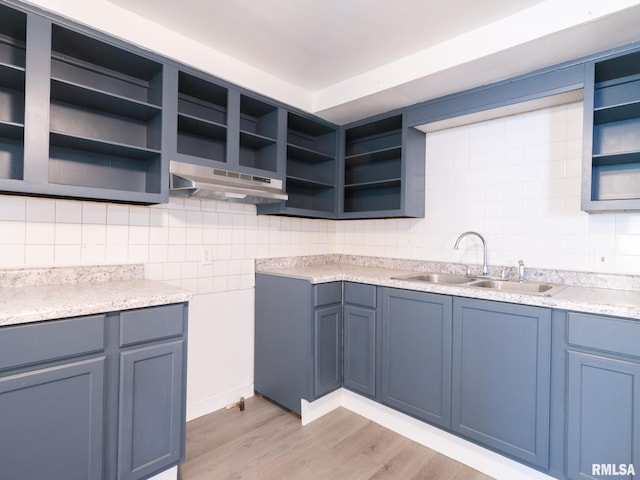 kitchen with open shelves, light wood-type flooring, under cabinet range hood, and a sink