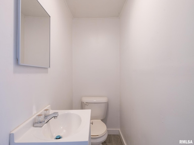 half bath with toilet, vanity, and baseboards