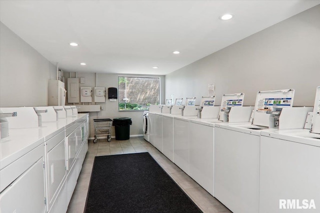 laundry area featuring washing machine and dryer, electric panel, and light tile patterned floors