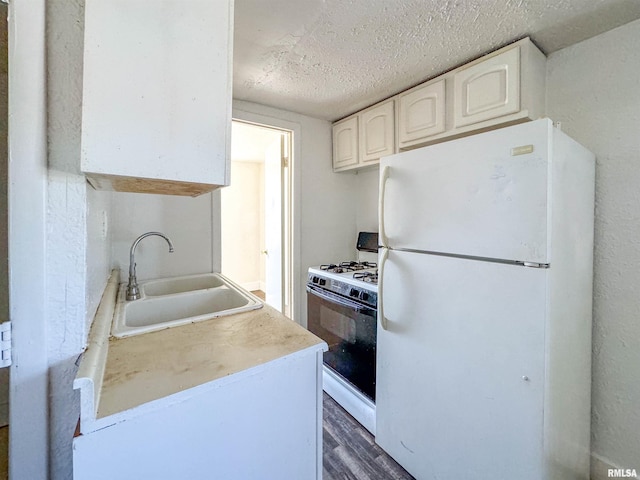 kitchen featuring dark hardwood / wood-style floors, sink, white cabinets, a textured ceiling, and white appliances