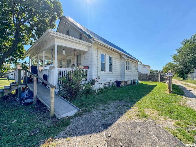 view of home's exterior with covered porch and a lawn