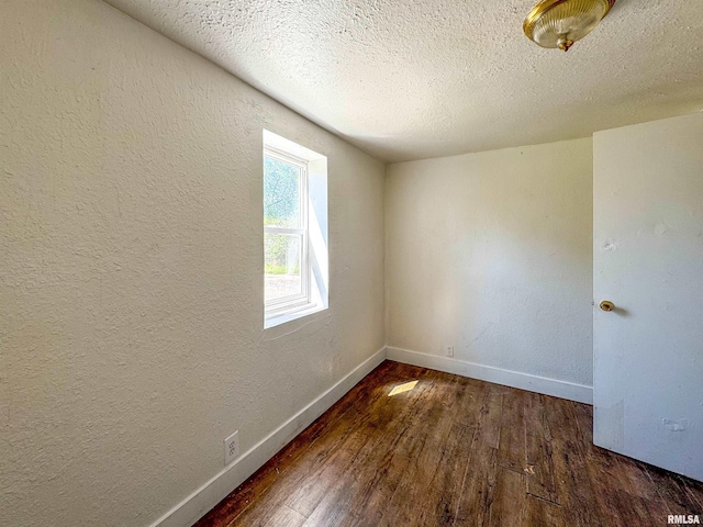 empty room with dark wood-type flooring and a textured ceiling