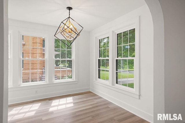 unfurnished dining area with a chandelier and light wood-type flooring