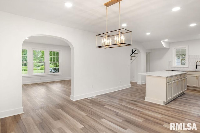 unfurnished dining area featuring plenty of natural light, sink, and light wood-type flooring