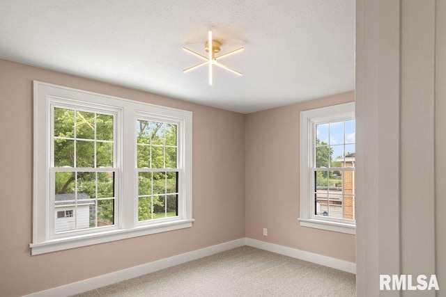 carpeted spare room with a textured ceiling and baseboards
