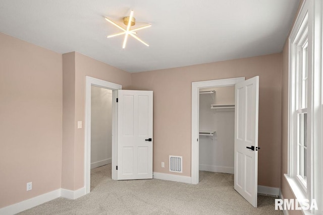 unfurnished bedroom featuring light carpet, a spacious closet, and a closet