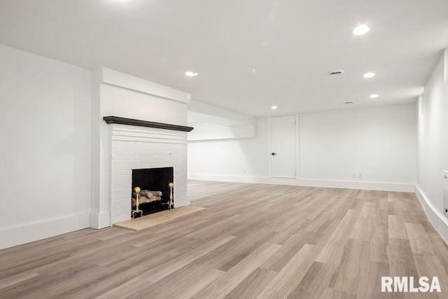 unfurnished living room featuring light wood-style flooring, recessed lighting, a brick fireplace, and baseboards