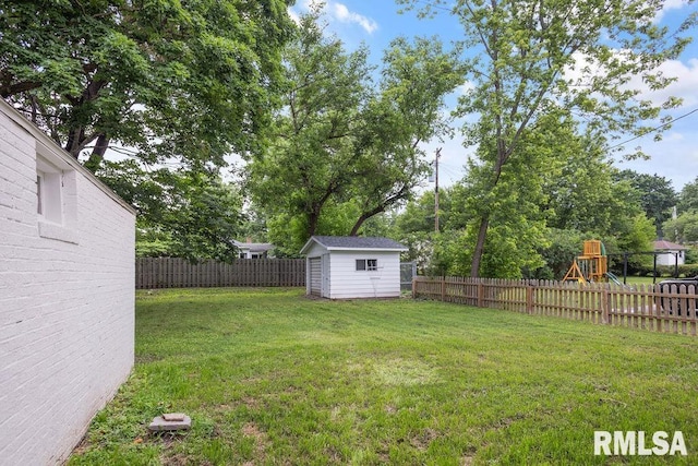 view of yard with a playground, an outbuilding, a fenced backyard, and a storage unit