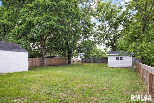 view of yard with a fenced backyard, a storage shed, and an outbuilding