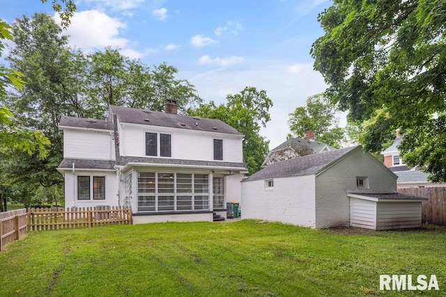 rear view of property featuring a storage shed, a sunroom, and a lawn