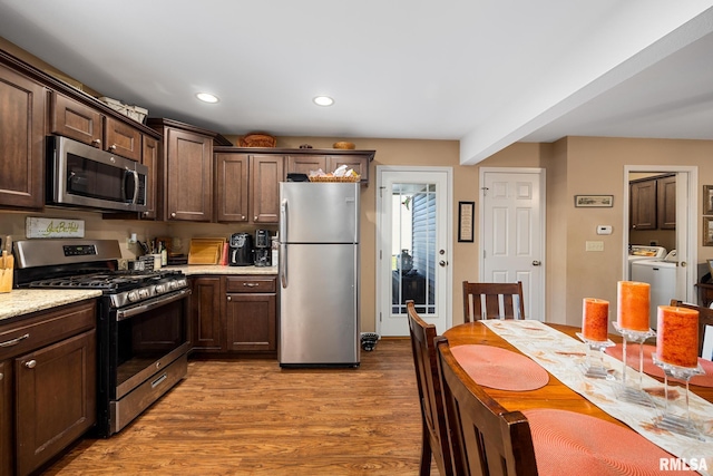 kitchen featuring appliances with stainless steel finishes, light hardwood / wood-style flooring, dark brown cabinets, and separate washer and dryer