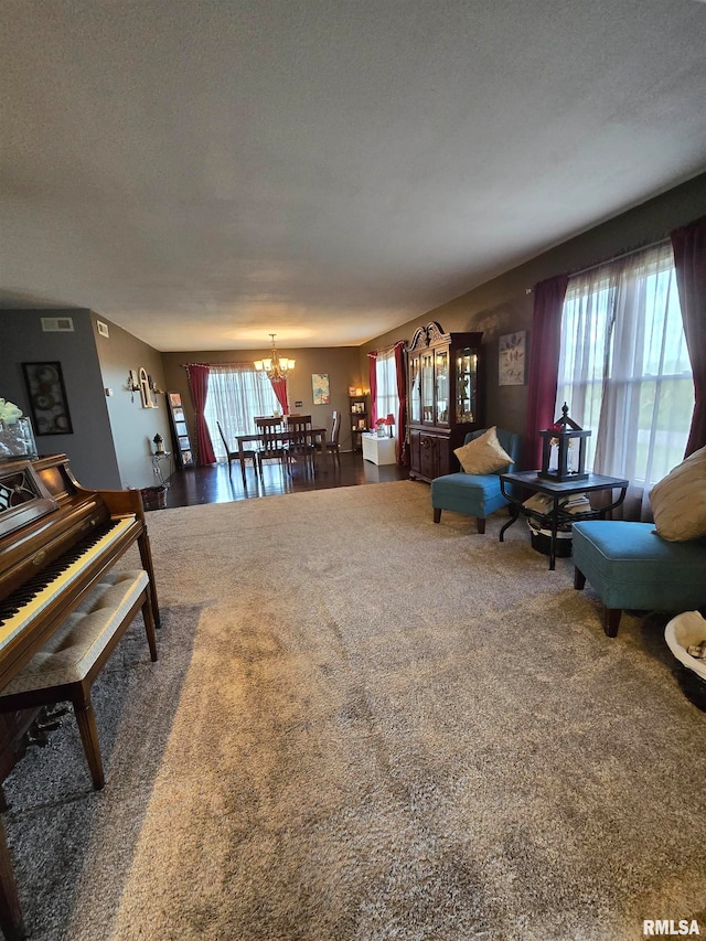 carpeted living room with a textured ceiling, plenty of natural light, and an inviting chandelier