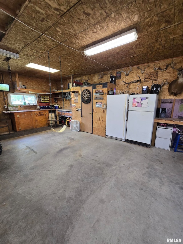 garage with white refrigerator and a workshop area