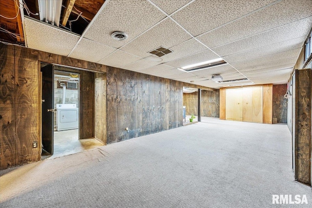 basement with washer / clothes dryer, carpet, a drop ceiling, and wood walls