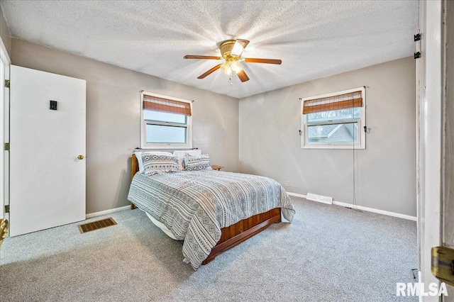 carpeted bedroom featuring ceiling fan, multiple windows, and a textured ceiling