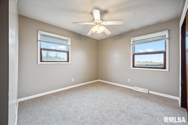 carpeted spare room with ceiling fan, a healthy amount of sunlight, and a textured ceiling