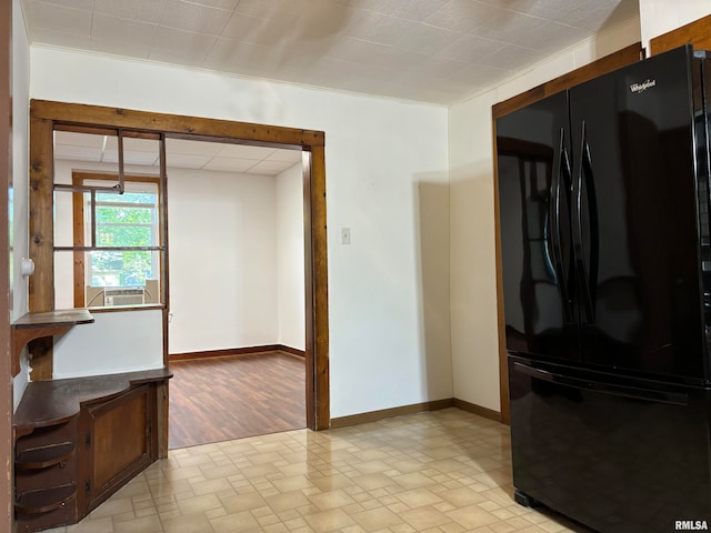 kitchen with black refrigerator, ornamental molding, and light hardwood / wood-style flooring