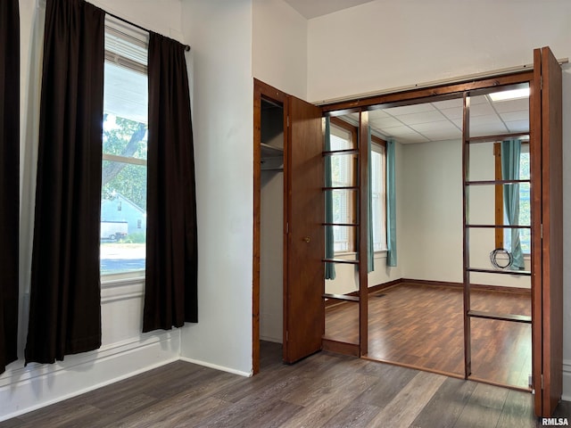 spare room with dark hardwood / wood-style flooring and a drop ceiling