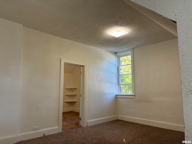 unfurnished bedroom featuring a closet, carpet, a spacious closet, and a textured ceiling