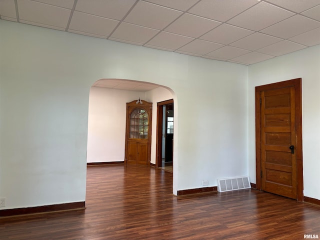 unfurnished room featuring dark wood-type flooring and a paneled ceiling