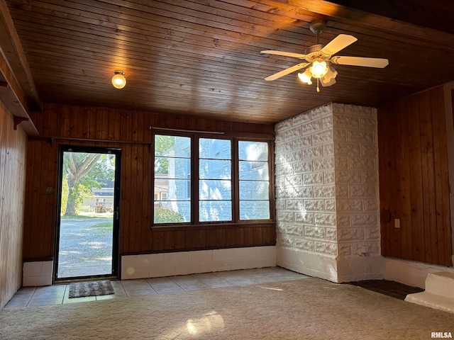 empty room featuring ceiling fan, light tile patterned floors, and wooden ceiling