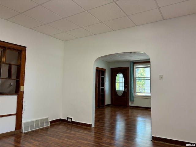 spare room with dark wood-type flooring and a paneled ceiling