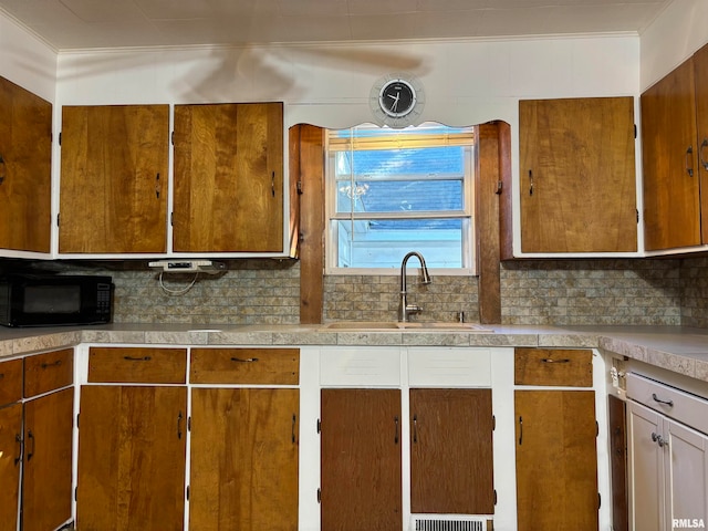 kitchen with ornamental molding, sink, and tasteful backsplash