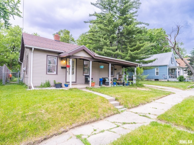 bungalow with a shingled roof, fence, a porch, a front yard, and a chimney