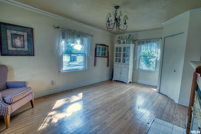 dining space with an inviting chandelier, ornamental molding, a textured ceiling, and light wood-type flooring