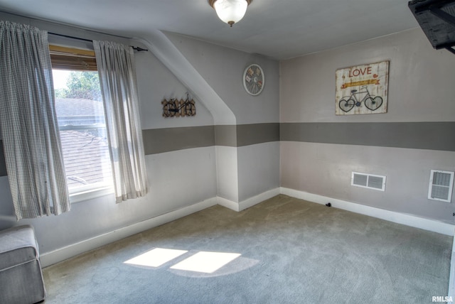 spare room featuring light colored carpet and lofted ceiling