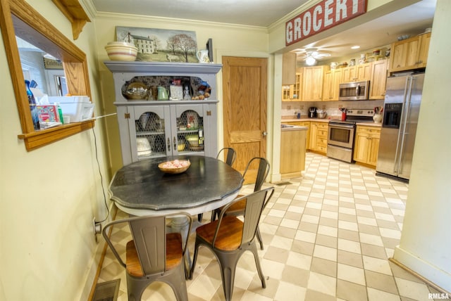 tiled dining space with ceiling fan and crown molding