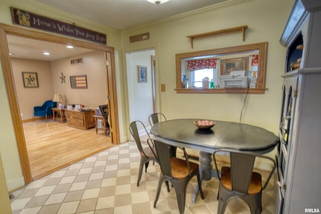 dining room with crown molding and light hardwood / wood-style floors