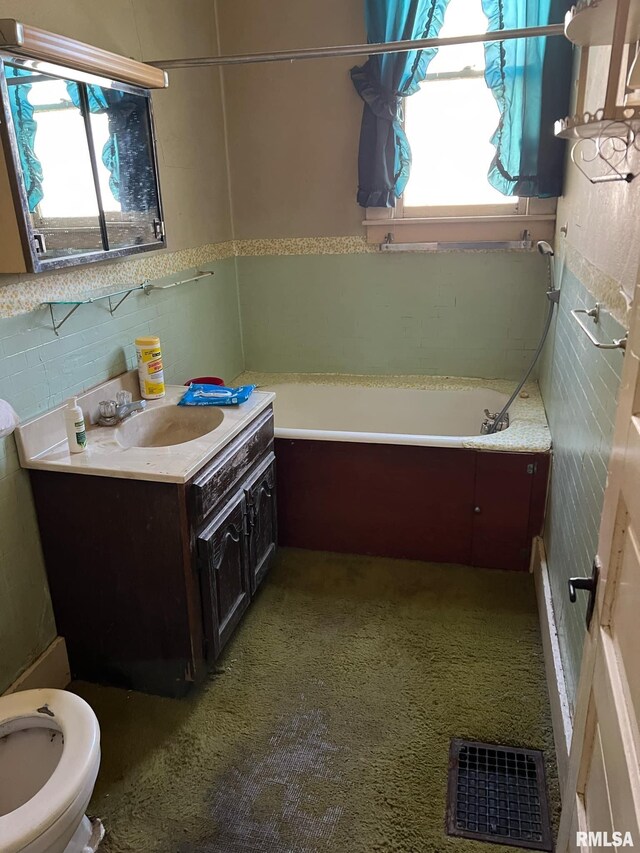 bathroom featuring vanity, toilet, plenty of natural light, and a washtub