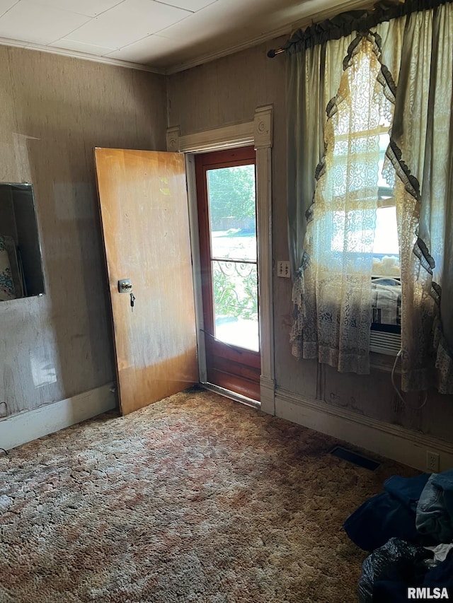 doorway to outside featuring crown molding and carpet flooring