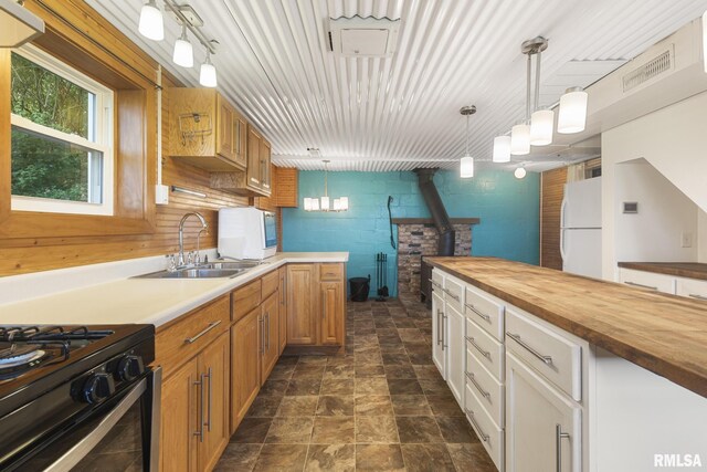 kitchen with white cabinets, sink, a wood stove, white fridge, and decorative light fixtures