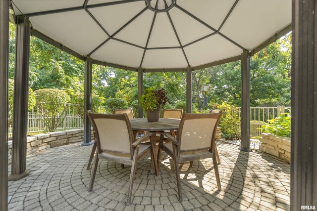 200 W Ravinwoods Rd, Peoria, IL 61615 - view of patio featuring outdoor dining space, a gazebo, and view of wooded area