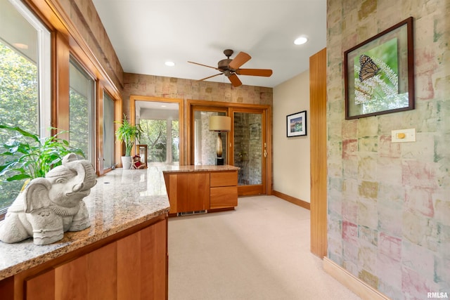 interior space with light carpet, ceiling fan, and light stone countertops