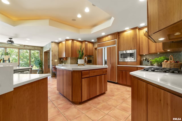 200 W Ravinwoods Rd, Peoria, IL 61615 - kitchen with a raised ceiling, built in appliances, brown cabinets, decorative backsplash, and recessed lighting